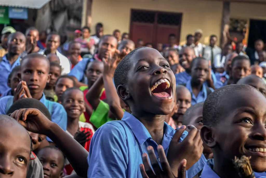 Group of children laughing and clapping outdoors – joyful community moment